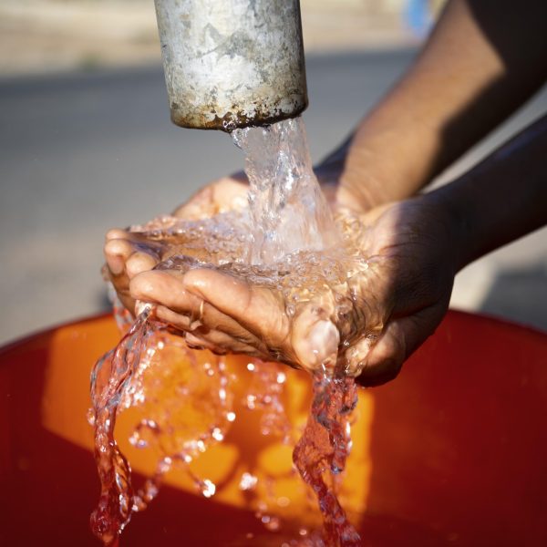 mulher-africana-servindo-agua-em-um-recipiente-ao-ar-livre