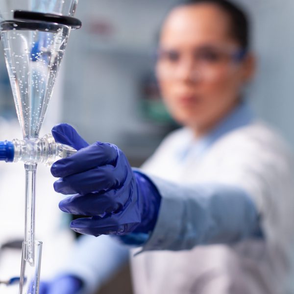 Specialist chemist woman working at biochemistry experiment using professional biology tools examining scientific chemistry research. Microbiologist doctor standing in hospital laboratory