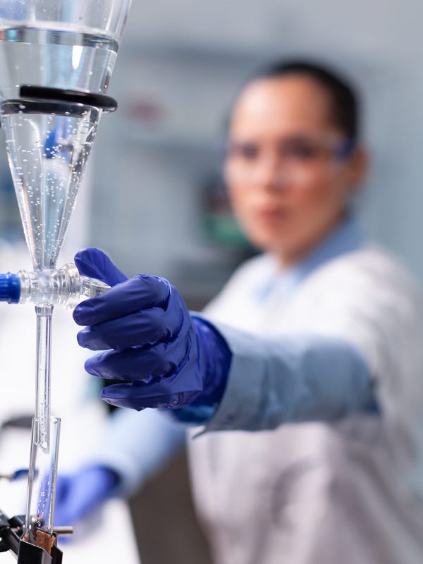 Specialist chemist woman working at biochemistry experiment using professional biology tools examining scientific chemistry research. Microbiologist doctor standing in hospital laboratory